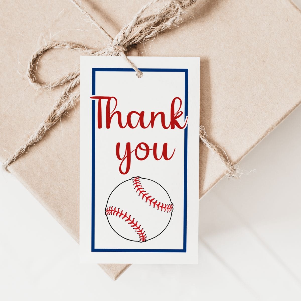 A gift wrapped in brown paper and tied with twine, featuring a tag with a baseball illustration and the words “Thank you” in red and script font.