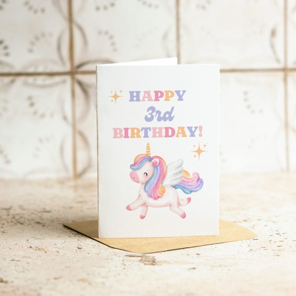 A Unicorn 3rd Birthday Card on a brown envelope features a cartoon winged unicorn with a rainbow mane and the text “HAPPY 3rd BIRTHDAY!” in pastel colors, surrounded by playful star accents.