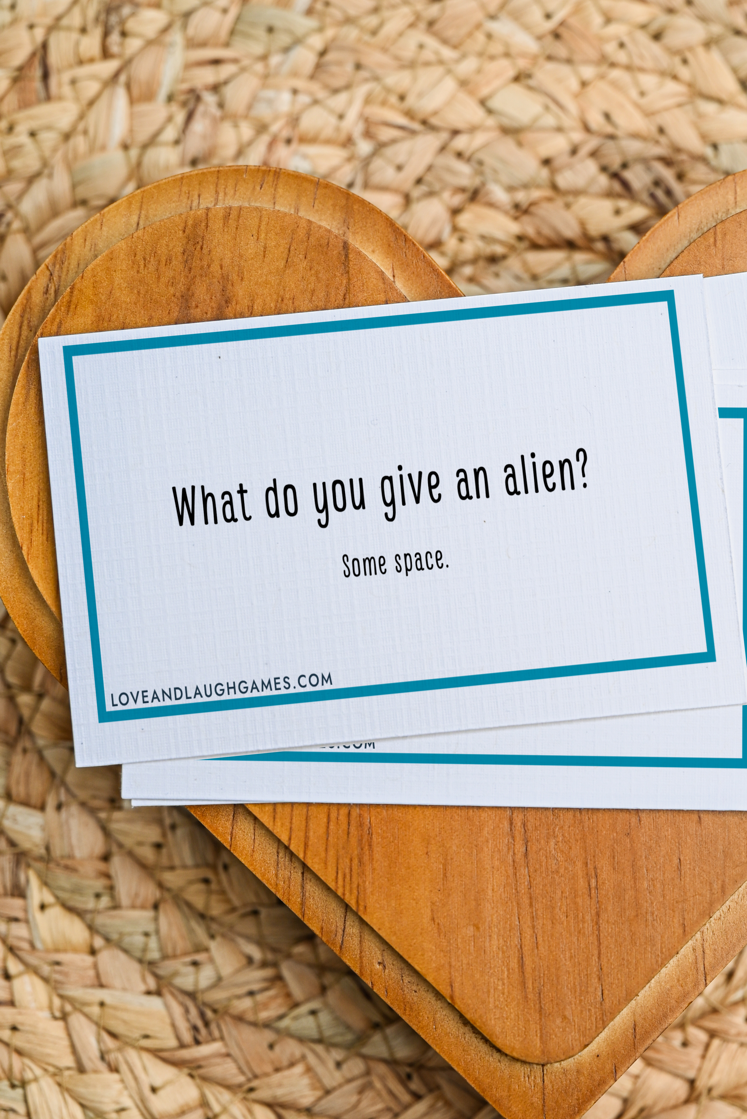 A card reads, “What do you give an alien? Some space.” The card rests on a wooden heart-shaped tray over a woven mat.